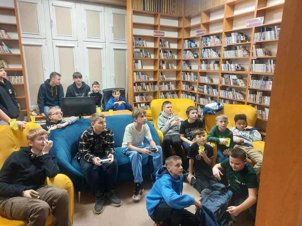 Grupa kilkunastu chłopców zgromadzonych w Wypożyczalni Zbiorów Audiowizualnych w trakcie turniejowych rozgrywek Fot. Dawid Szymczak